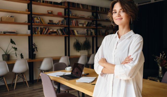 young-attractive-woman-white-shirt-dreamily-looking-camera-with-desk-background-modern-office