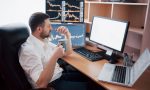 young-businessman-is-sitting-office-table-working-computer-with-many-monitors-diagrams-monitor-stock-broker-analyzes-binary-options-charts-hipster-man-drinking-coffee-studying