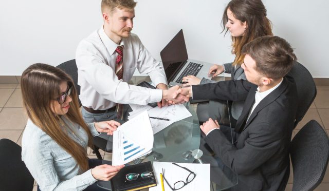 elevated-view-businessman-shaking-hands-with-his-partner-workplace